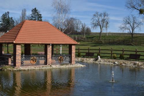 a gazebo in the middle of a pond with a swan at Berényi Fogadó in Nagykanizsa