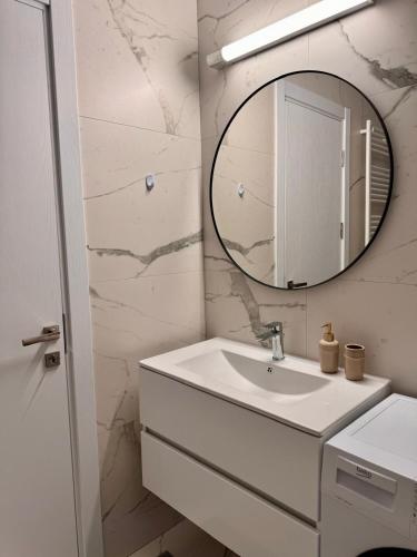 a white bathroom with a sink and a mirror at Cozy Apartment in Bucharest