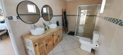 Un baño con dos lavabos y un inodoro y espejos. en Joy Haven - Open Plan Studio, en Centurion