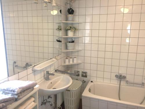 a white tiled bathroom with a sink and a tub at Landhaus Westerweg - Familie Petersen in Wanderup