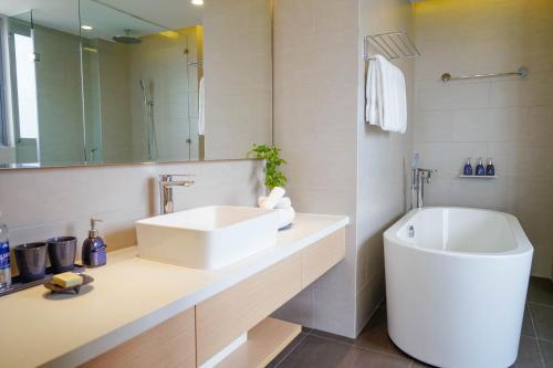 a white bathroom with a sink and a tub at Naman Retreat in Da Nang