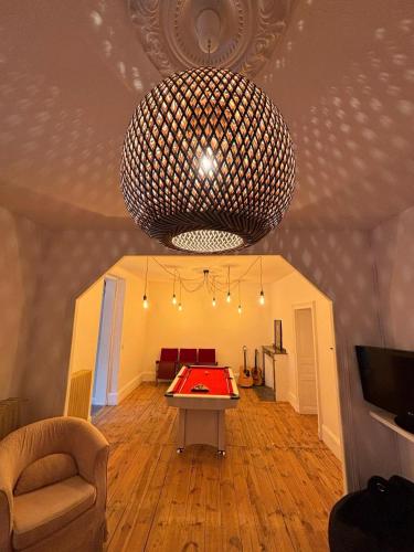 une pièce avec une table de ping-pong et un grand lustre dans l'établissement l'étape DECAZEVILLE, à Decazeville