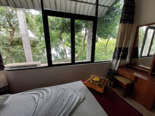 a bedroom with three windows and a bed with a pillow at Lake Wave Hotel in Anuradhapura