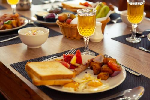 a table with a plate of breakfast food and two glasses of beer at Hotel Gyan Gauri Palace in Beni