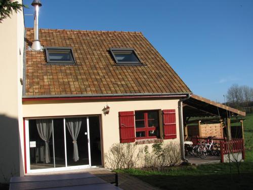 a small house with red doors and a roof at La Bergerie du festel in Saint-Riquier