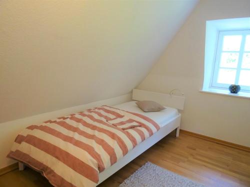 a bedroom with a bed with a striped comforter and a window at Kleines Reethaus Johannsen - mit geschmackvoller Einrichtung und tollem Garten in Silberstedt