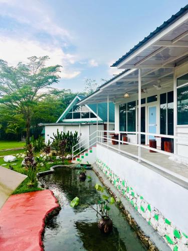 a house with a koi pond in front of it at KASIH SAYANG Farmstay山下人家 in Kluang