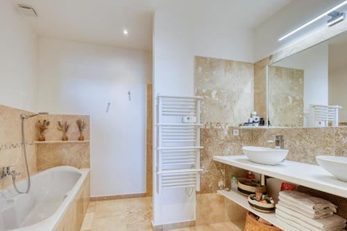 La salle de bains est pourvue d'une baignoire, de 2 lavabos et d'une baignoire. dans l'établissement Superbe villa au calme avec vue, à Ollioules