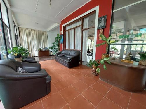 a lobby with black leather furniture and a red wall at Lake Wave Hotel in Anuradhapura