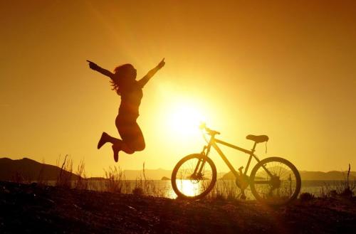 a woman jumping in the air next to a bike at Villa Margarita 3 Bedroom Villa with Private Pool and Sea View in Naxos Chora