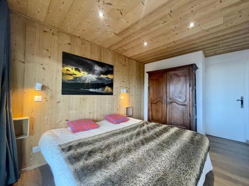 une chambre avec un grand lit avec un mur en bois dans l'établissement Homency - Résidence Plein Ciel A, à L'Alpe-d'Huez