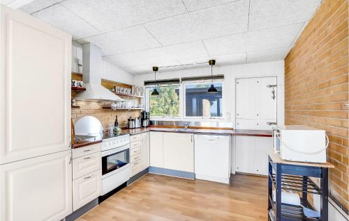 a kitchen with white cabinets and a brick wall at Cozy Home In Vesløs With House Sea View in Øsløs