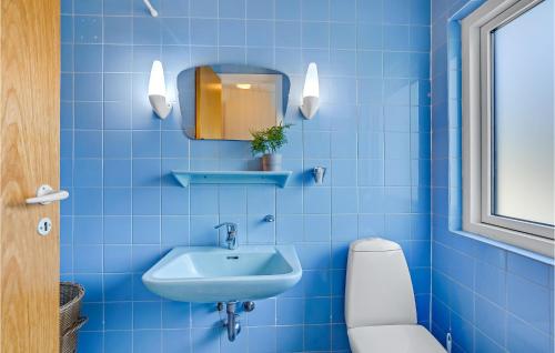 a blue tiled bathroom with a sink and a toilet at Cozy Home In Vesløs With House Sea View in Øsløs