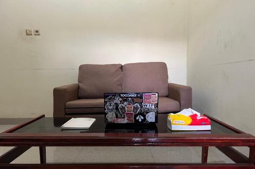 a coffee table in front of a couch with a chair at Hotel O Kos Rian in Sungguminasa