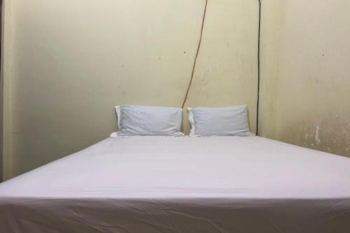 a bed in a room with two pillows on it at Hotel O Kos Rian in Sungguminasa