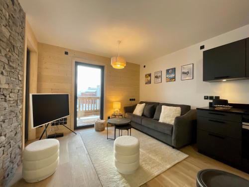 un salon avec un canapé et une télévision à écran plat dans l'établissement Homency - Résidence Chalets du Golf - Albatros A203, à L'Alpe-d'Huez