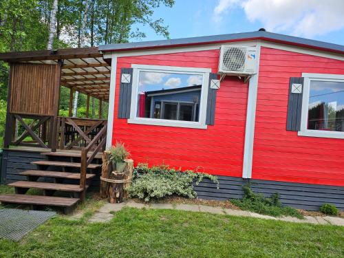 a red tiny house with a porch and stairs at Domek letniskowy - czerwony całoroczny in Stegers
