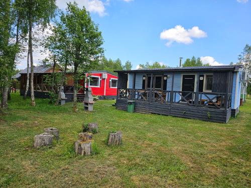a small house in a yard with logs in the grass at Domek letniskowy - czerwony całoroczny in Stegers