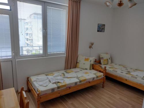 two beds in a room with two windows at Къща за гости Янка in Nesebar
