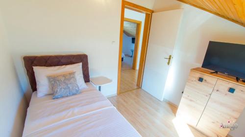 a bedroom with a bed and a flat screen tv at Villa Pearl- with private pool in Blagaj