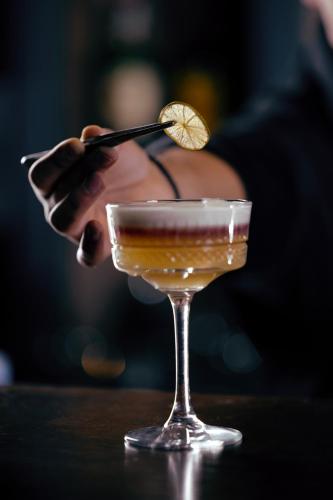 a person is stirring a drink in a martini glass at Marco Polo Hotel Gudauri in Gudauri