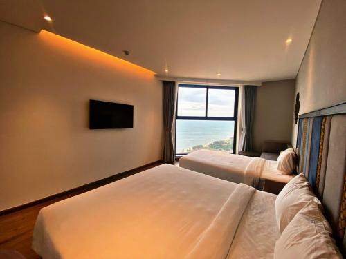 a hotel room with two beds and a large window at APEC Mandala Mũi Né in Mui Ne
