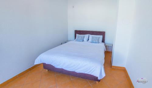 a bedroom with a white bed with blue pillows at Villa Pearl- with private pool in Blagaj