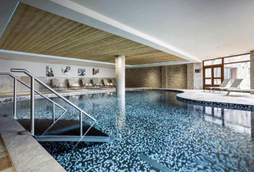 une piscine avec de l'eau bleue dans un immeuble dans l'établissement Homency - Résidence Daria-i-Nor 202, à L'Alpe-d'Huez
