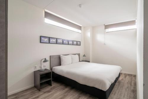 a bedroom with a white bed and a night stand at YAYS Amsterdam Prince Island by Numa in Amsterdam