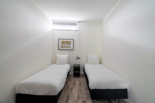 two beds in a room with white walls at YAYS Amsterdam Prince Island by Numa in Amsterdam