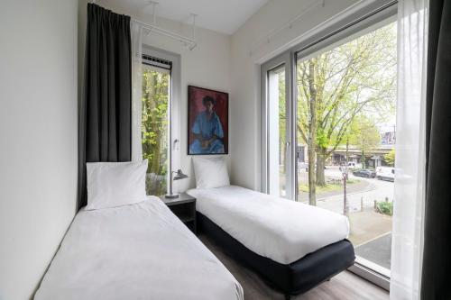two beds in a room with a window at YAYS Amsterdam Prince Island by Numa in Amsterdam
