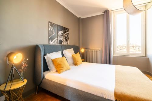 a bedroom with a large bed with yellow pillows at Dupain & Dubeurre Appart'hôtel - Parking en supp in Limoges