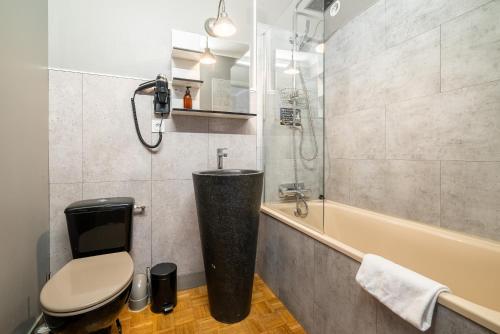 a bathroom with a toilet and a sink and a tub at Dupain & Dubeurre Appart'hôtel - Parking en supp in Limoges