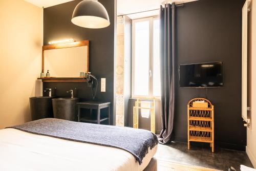 a bedroom with a bed and a mirror and a television at Dupain & Dubeurre Appart'hôtel - Parking en supp in Limoges
