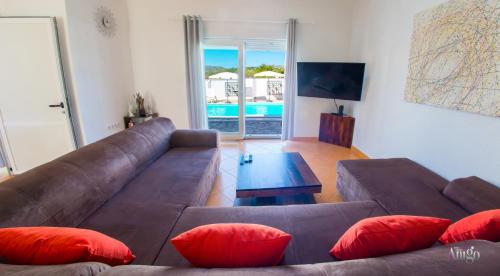 a living room with a brown couch and red pillows at Villa Pearl- with private pool in Blagaj