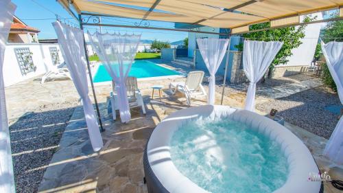 a bath tub in a backyard with a pool at Villa Pearl- with private pool in Blagaj