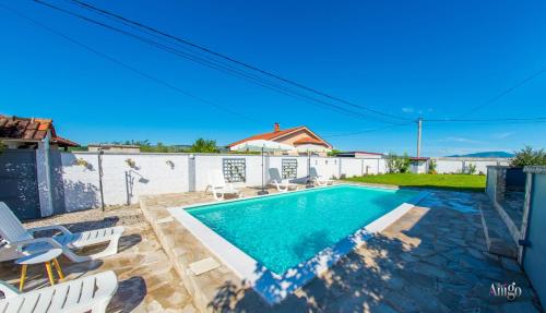 a swimming pool in a backyard with chairs and a house at Villa Pearl- with private pool in Blagaj