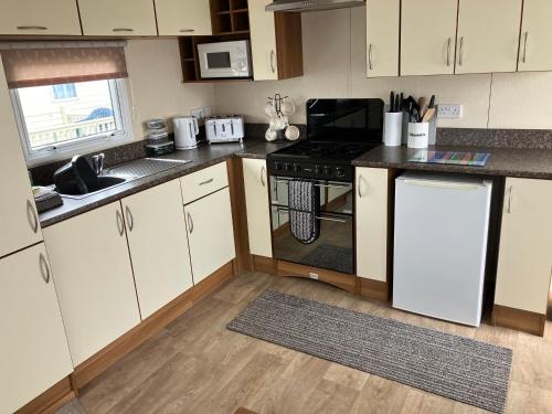 a kitchen with white cabinets and a stove top oven at CSL Holidays in Skegness