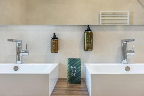 a bathroom with two sinks and two bottles on the wall at Schartneralm Zirbel Family in Collalbo