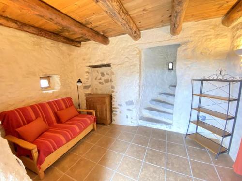 - un salon avec un canapé rouge et un escalier dans l'établissement LA CONFISERIE, à Saint-Sauveur-de-Cruzières