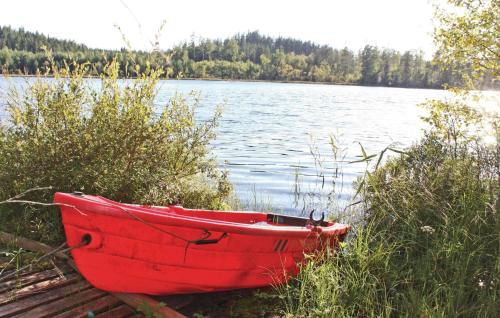 a red boat sitting on the shore of a lake at Stunning Home In Svenljunga With Wifi in Grannäs