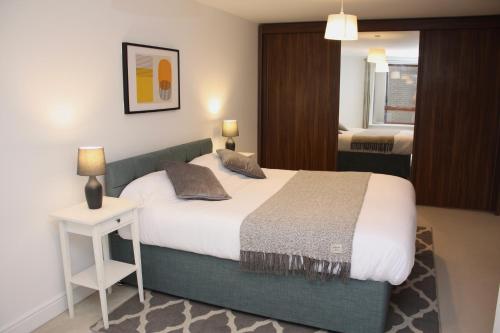 a bedroom with a large bed and a table with a lamp at Spacious 2 Bed 2 Bath Apartment & Free Parking - LGW 10min drive in Crawley