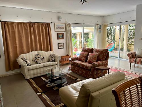a living room with a couch and chairs and a table at Two bedroom villa with private swimming pool and garden in Almadies in Dakar
