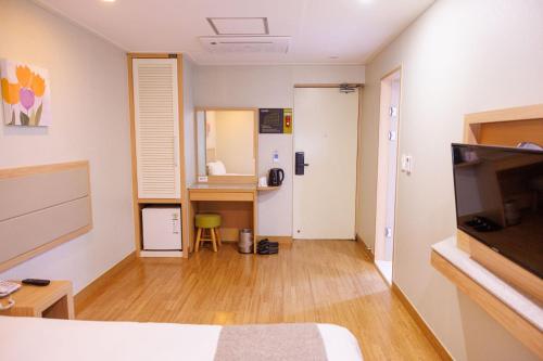 a room with a bed and a desk and a television at Jeju Robero in Jeju