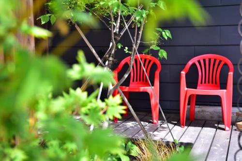 two red chairs sitting next to a tree at HOTEL Sauna&Living in Iwanuma