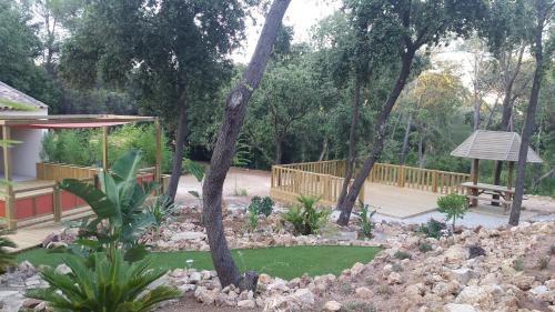 a garden with a table and a bench and trees at Le Mas des Bois in Le Muy