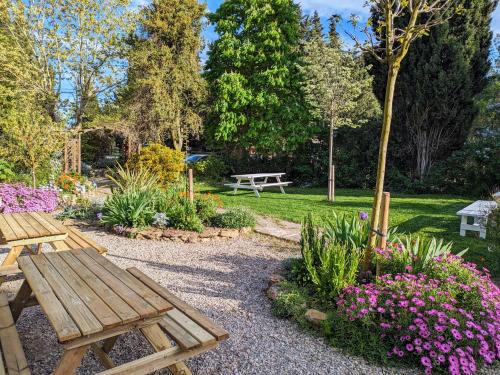 un parc avec deux bancs en bois et des fleurs dans l'établissement Pommayrac nature, à Verzeille