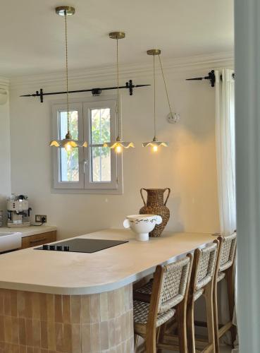 Il dispose d'une cuisine avec un îlot pourvu de chaises et de lumières. dans l'établissement Appartement Bastide Le Moulin, à Grimaud