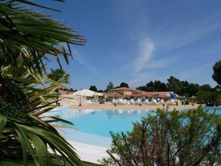 une grande piscine avec tables et parasols dans un complexe hôtelier dans l'établissement Mobil-home 949, aux Mathes