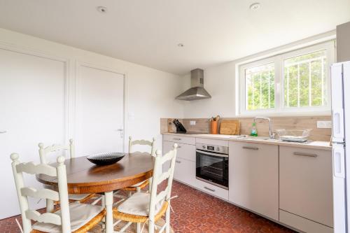 une cuisine avec des armoires blanches et une table en bois dans l'établissement La maison des chevaux, à Saint-Vran